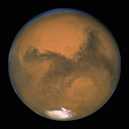 Một bức ảnh chụp một mặt đầy đủ ánh sáng của sao Hỏa, cho thấy màu nâu đỏ trên bề mặt của nó và một đốm trắng ở mặt phía nam.