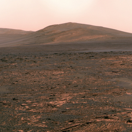 Một bức ảnh chụp bề mặt sao Hỏa với một ngọn đồi ở hậu cảnh và rất nhiều tảng đá nhỏ ở tiền cảnh.