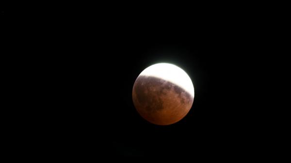 Mặt Trăng bị che khuất một phần trên bầu trời đêm. Một nửa của Mặt trăng được bao phủ bởi một bóng râm màu đỏ.